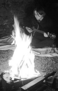 Playing guitar beyond a campfire